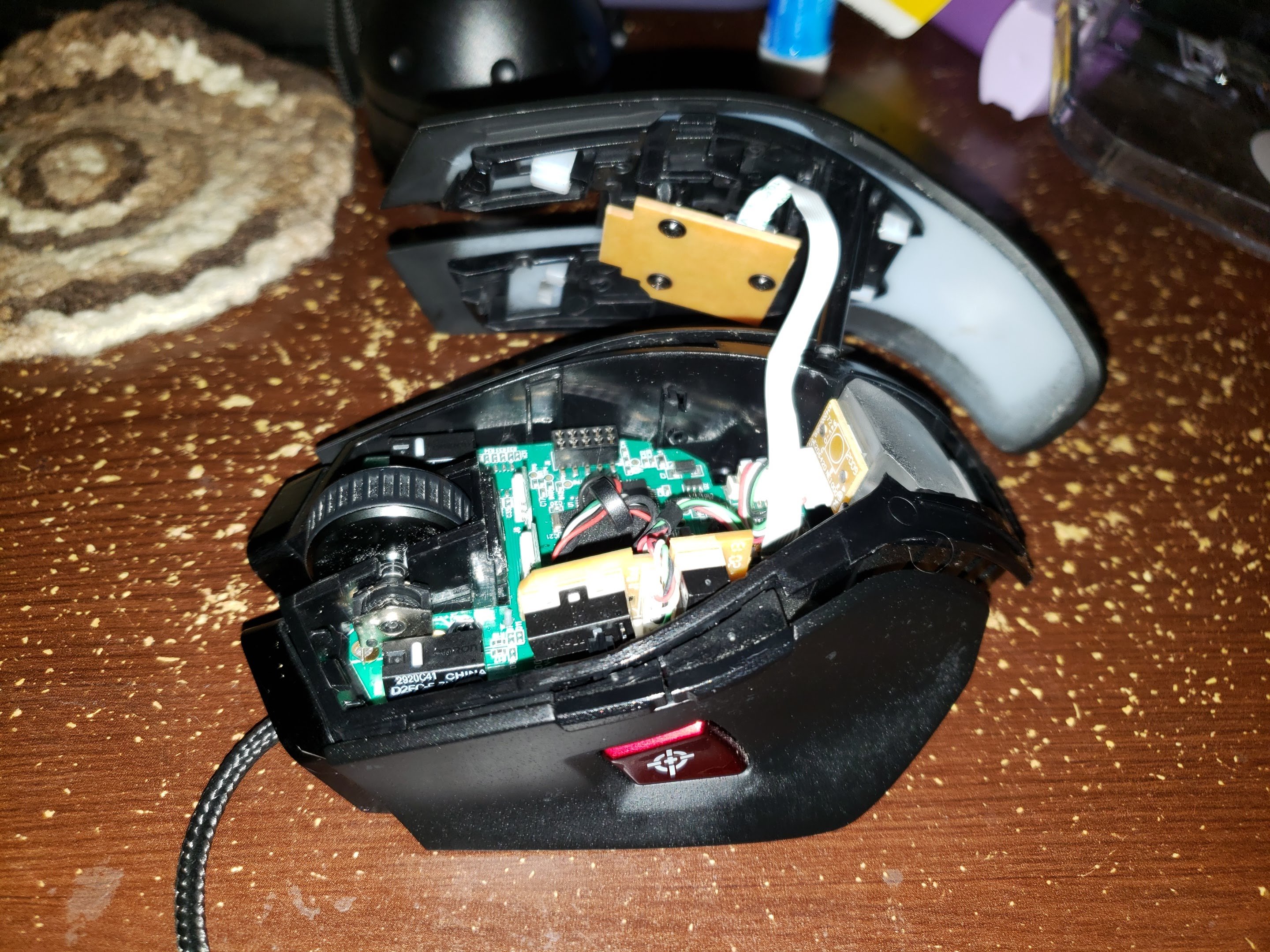 Photo of a disassembled Corsair M65 mouse with the lid hanging off