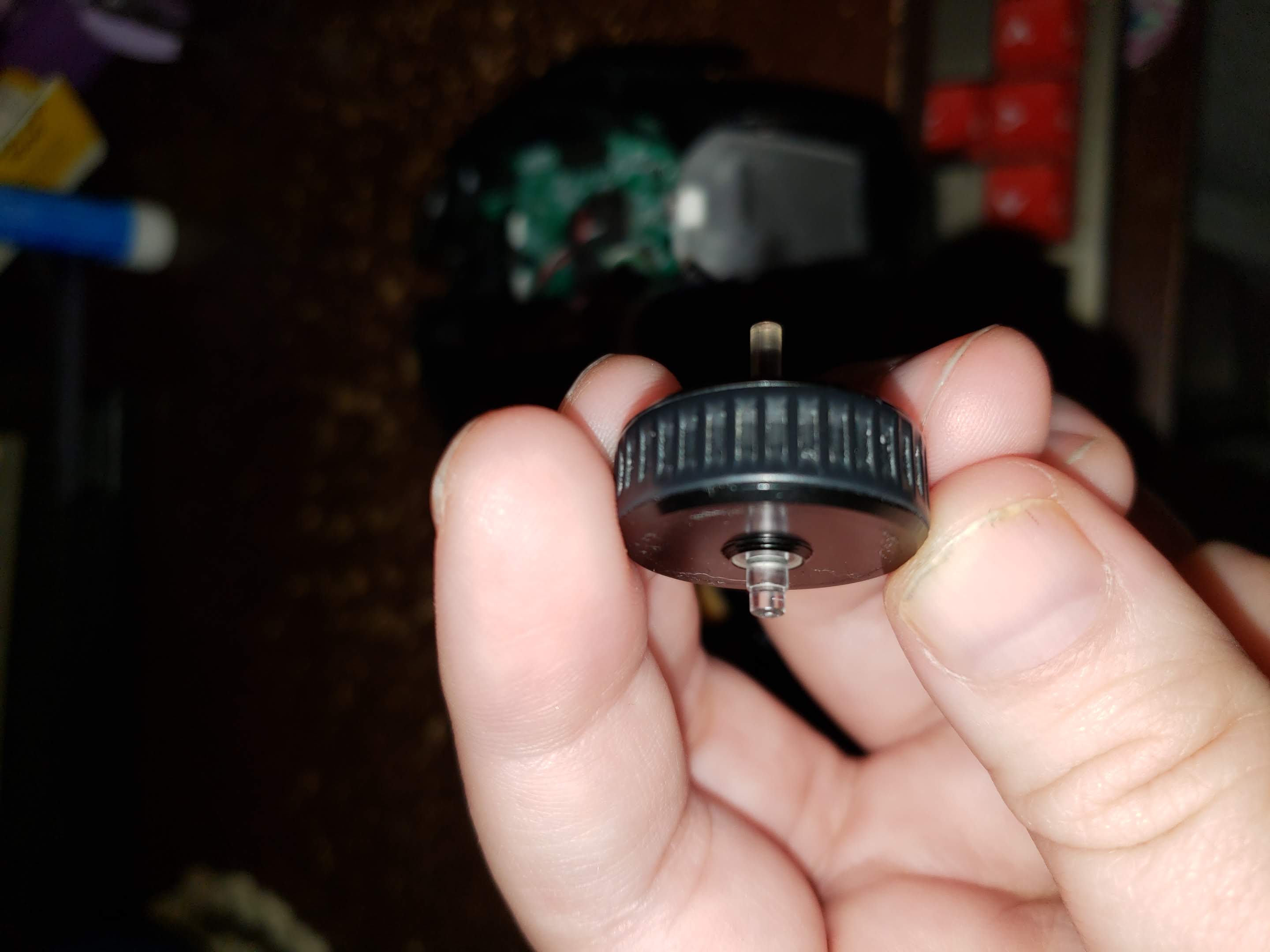 Photo of a mouse wheel removed from the mouse. The post closest to the camera is shorter than it should be